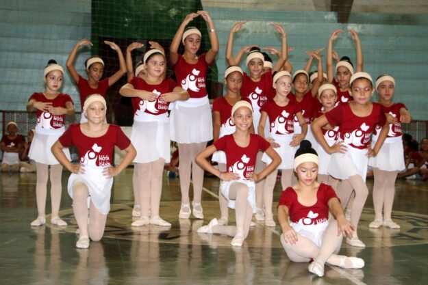 Apresentação de balé: Jovens dançarinas em uniformes vermelhos e brancos. Um grupo de dançarinas em uniformes de balé vermelhos e brancos, posando em uma quadra poliesportiva.