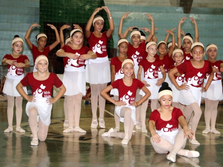 Apresentação de balé: Jovens dançarinas em uniformes vermelhos e brancos. Um grupo de dançarinas em uniformes de balé vermelhos e brancos, posando em uma quadra poliesportiva.