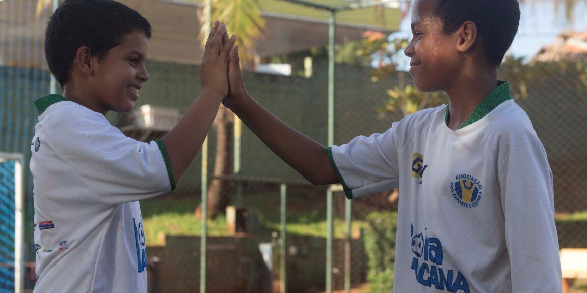 Amizade e espírito de equipe no projeto esportivo. Jovens participantes de projeto social esportivo celebram com um high-five, mostrando espírito de equipe.