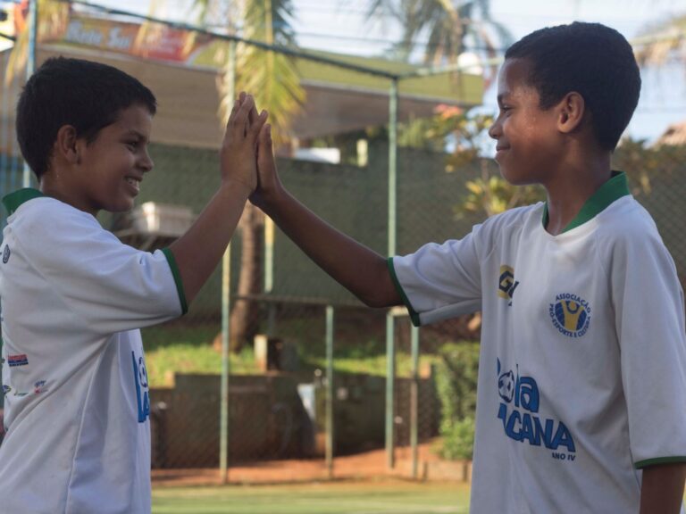 Amizade e espírito de equipe no projeto esportivo. Jovens participantes de projeto social esportivo celebram com um high-five, mostrando espírito de equipe.