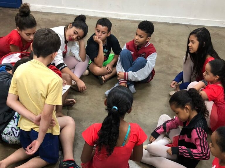 Roda de conversa e interação entre crianças. Grupo de crianças sentados em círculo no chão de uma sala, participando de uma roda de conversa.