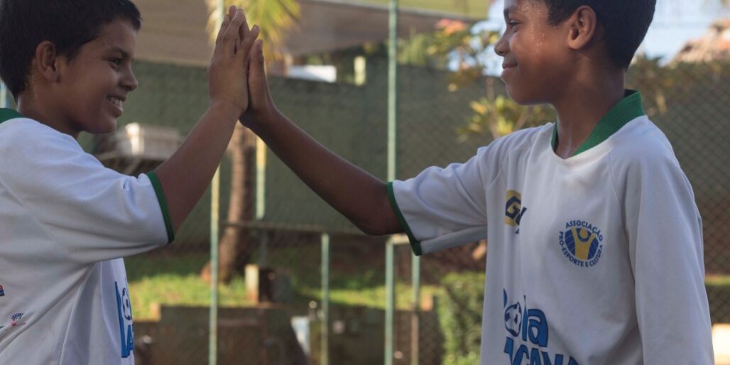 Amizade e espírito de equipe no projeto esportivo. Jovens participantes de projeto social esportivo celebram com um high-five, mostrando espírito de equipe.