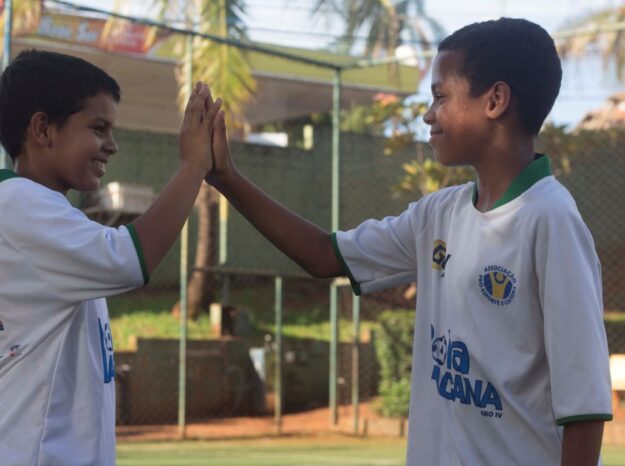 Amizade e espírito de equipe no projeto esportivo. Jovens participantes de projeto social esportivo celebram com um high-five, mostrando espírito de equipe.