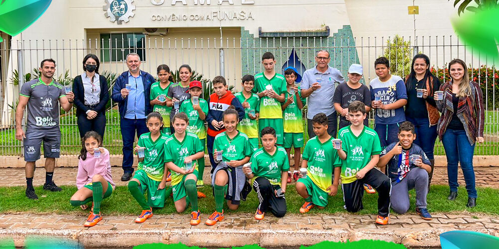Time esportivo de crianças e adultos em frente ao SAMAE em comemoração ao Dia do Meio Ambiente. Grupo de adultos e crianças de uniforme verde posa em frente ao prédio do SAMAE. "05 JUNHO DIA DO MEIO AMBIENTE".