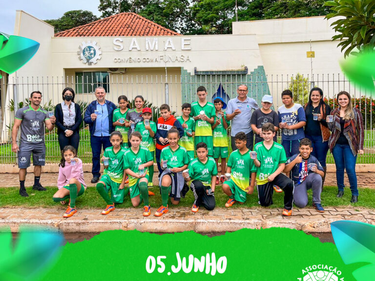 Time esportivo de crianças e adultos em frente ao SAMAE em comemoração ao Dia do Meio Ambiente. Grupo de adultos e crianças de uniforme verde posa em frente ao prédio do SAMAE. "05 JUNHO DIA DO MEIO AMBIENTE".