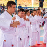 Alunos de artes marciais em quimono branco em formação, mostrando disciplina e companheirismo.