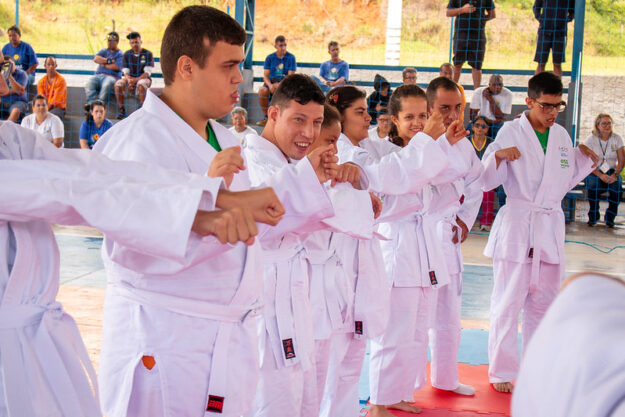 Alunos de artes marciais em quimono branco em formação, mostrando disciplina e companheirismo.