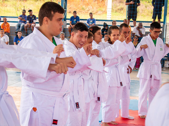 Alunos de artes marciais em quimono branco em formação, mostrando disciplina e companheirismo.